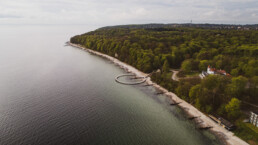 Luftfoto af Den Uendelige Bro i Aarhus, en cirkelformet badebro ved skov og strand – dronefoto af Kasper Hornbæk.
