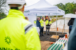 Repræsentanter fra Innargi og samarbejdspartnere i dialog under pressemøde ved et boringsanlæg, afholdt under telt i regnvejr.