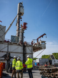 Tre medarbejdere fra Innargi i gule jakker står foran stor boreplatform og diskuterer installationen.
