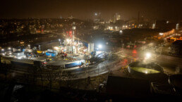 Aftenfoto af oplyst boreplads i byen, hvor Innargi arbejder med geotermisk energiudvinding.