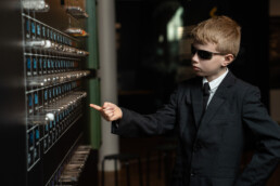 Barn i sort jakkesæt og solbriller peger på grundstoffer i det periodiske system på Science Museerne i Aarhus.