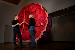 To personer betragter en farverig, strikket kunstinstallation på en særudstilling hos Science Museerne i Aarhus.