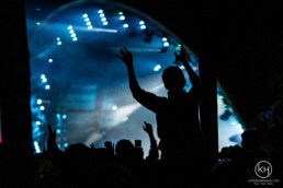 Publikum i silhuet med hævede hænder foran scenen, Smukfest musikfestival med blå scene-belysning. Foto af Kasper Hornbæk.