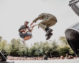 Hugorm springer energisk i luften med guitar foran publikum på Smukfest. Dynamisk koncertfoto af Kasper Hornbæk.