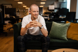 Portræt af mand i hvid t-shirt i moderne kontormiljø – professionel erhvervsfotografering til virksomhedens visuelle identitet.