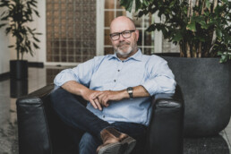 Professionelt virksomhedsprofil billede af ældre mand i afslappet loungeområde – corporate portræt med personlighed