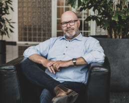 Professionelt virksomhedsprofil billede af ældre mand i afslappet loungeområde – corporate portræt med personlighed