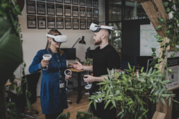 Dynamisk kontorfoto af kollegaer med VR-headsets omgivet af planter – visuelt indhold til tech og innovation
